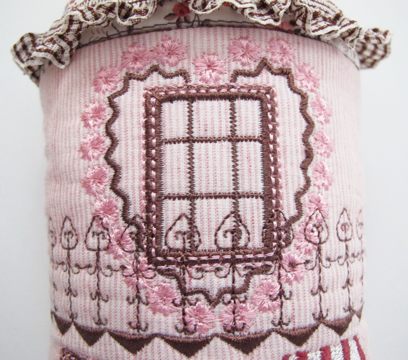 Country Chic Machine Embroidery Designs by Stitchingart. Door hanging, country style with house, windows, fencing, flowers in pot.